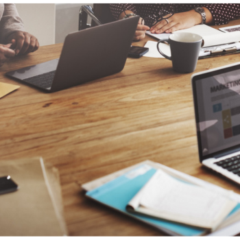 Digital marketing team working on laptops and strategy documents in a meeting room